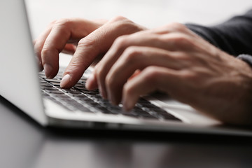 Canvas Print - Male hands typing on laptop keyboard at table closeup