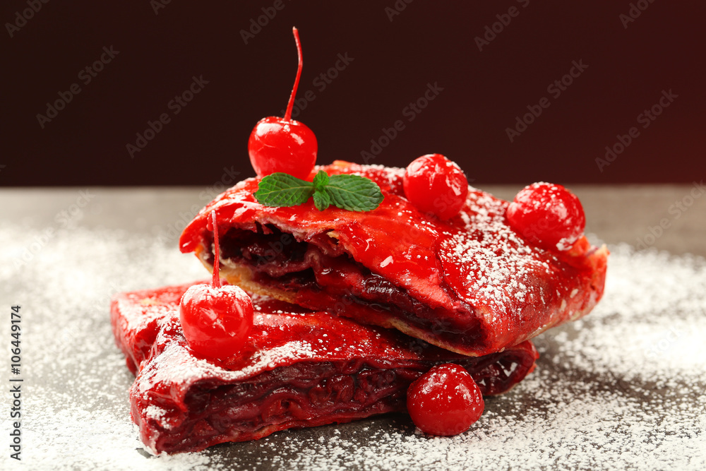 Powdered cherry strudel with mint on dark red background