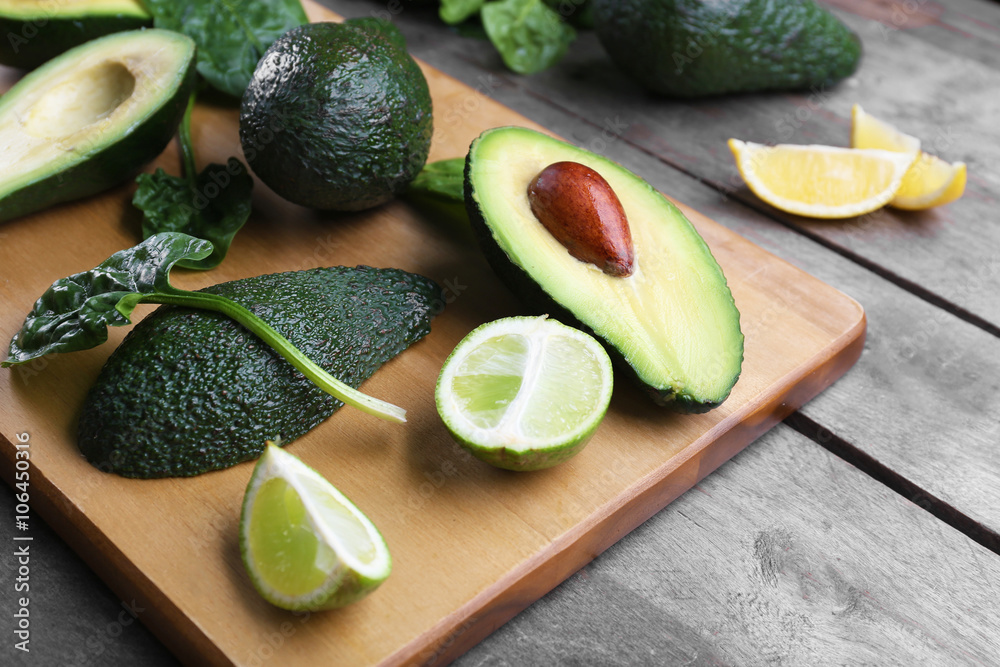 Sliced avocado with lime and spinach on wooden cutting board