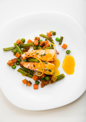 Wall Mural - Baked salmon with green beans, carrots, green peas, thyme and orange sauce on a white plate, top view