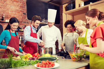 Wall Mural - happy friends and chef cook cooking in kitchen