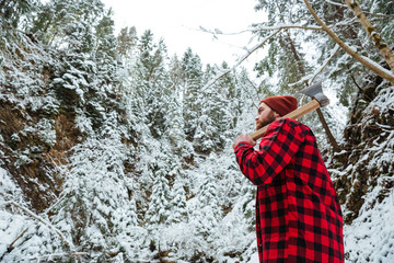 Poster - Bearded man with axe walking in mountain winter forest