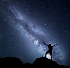Wall Mural - landscape with milky way. night sky with stars and silhouette of a happy climber with backpack and r