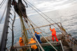 Fishermen in waterproof clothing on the deck of the fishing vess