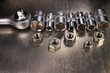 Socket wrench and set of stainless steel hex sockets with nuts on shiny metal background