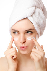 Young woman apply  cosmetic cream on a clean fresh face by both hands