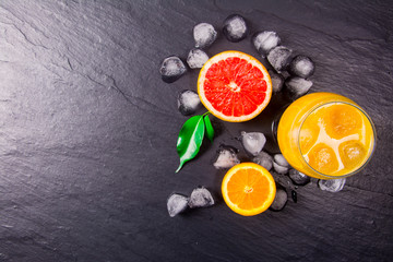 Wall Mural - Fresh orange juice with ice on dark stone background