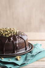 Chocolate Cake With Ganache And Pistachios Over Wooden Backgroun