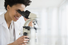 Black Scientist Using Microscope In Lab