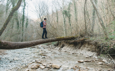 Hiker crossing river on tree trunk