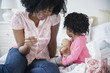 © JGI/Jamie Grill/Blend Images - Mother checking daughter's temperature on bed