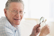 © JGI/Tom Grill/Blend Images - Senior Caucasian man examining stamp with magnifying glass