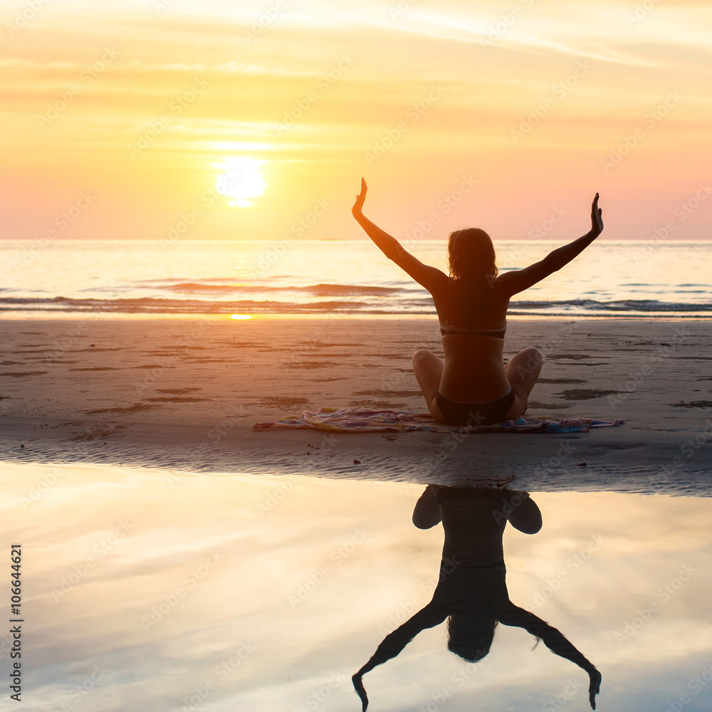 female silhouette doing yoga exercise at beautiful sunset on the sea beach healthy lifestyle wall mural de visu wallsheaven