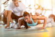© luckybusiness - woman doing push ups under supervision of a trainer