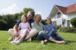 © Westend61 - Happy family sitting on lawn in garden