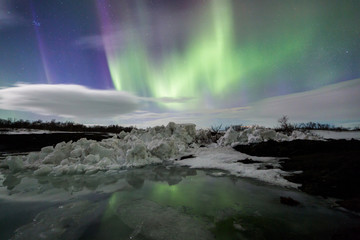 Wall Mural - northern lights above an iceberg in a lagoon