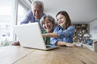 © Westend61 - Grandparents and their granddaughter having fun with laptop at home