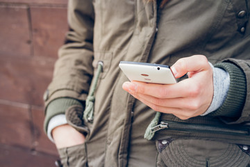 Girl in the green jacket holding a smartphone in one hand on a b