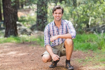 Wall Mural - Portrait of young man crouching on field 