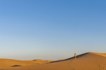 Woman Walking Over Sand Dunes