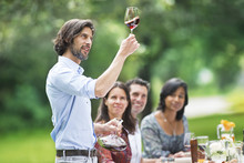 Man Tasting Red Wine At A Garden Party