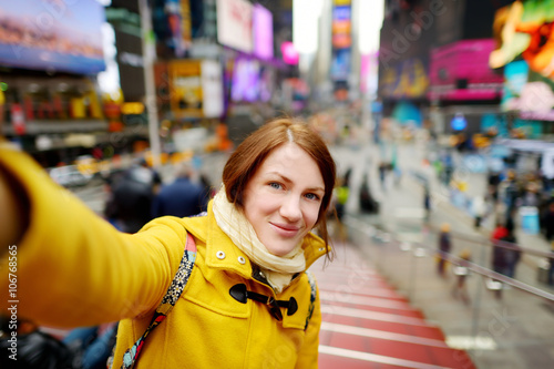 Beautiful young woman taking a selfie with her smartphone on Times Square Poster
