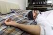 © Westend61 - Businessman lying on his bed with tie covering his eyes