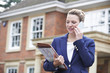 © highwaystarz - Female Realtor On Phone Outside Residential Property