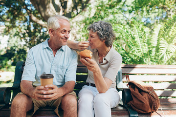 Wall Mural - Loving senior couple sitting on a park bench