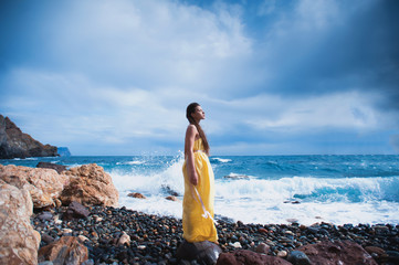 Girl standing on the beach against the sky and the sea, lifestyle, recreation, solitude, meditation