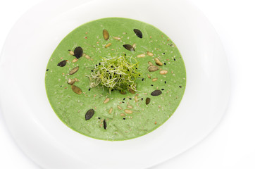 spinach cream soup in a white plate on a white background.