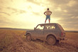 © Aliyev Alexei Sergeevich/Blend Images - Mari man standing on car roof in rural field