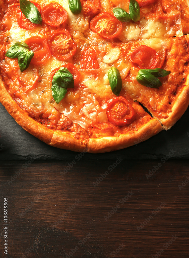Margherita pizza on slate plate over wooden background