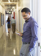© Sam Diephuis/Blend Images - Black businessman using cell phone in office hallway