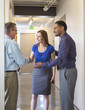 © Sam Diephuis/Blend Images - Business people shaking hands in office hallway