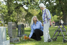 Caucasian Mother And Daughter Visiting Grave In Cemetery
