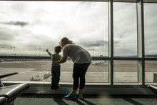 Mother And Son Looking Out Airport Window