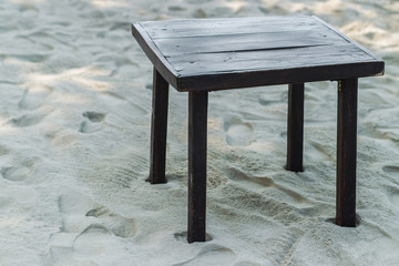 Old wooden table on the sand at the beach