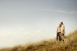 © Chris Clor/Blend Images - Caucasian couple walking dog on grassy dunes