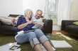 © Jasper Cole/Blend Images - Older couple looking at photographs in living room