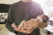 Father Holding Newborn Baby In Bedroom