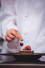 Wall Mural - Chef putting a cherry on a dessert