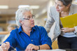 © Marc Romanelli/Blend Images - Teacher helping adult student in library