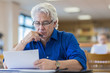 © Marc Romanelli/Blend Images - Man reading paperwork in library
