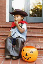 Mixed Race Boy Dressed As Cowboy Eating Halloween Candy