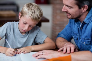 Wall Mural - Father helping son with his homework in kitchen