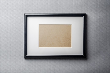 Black plain empty thin wood picture frame with white mat passe-partout on grey bricks background