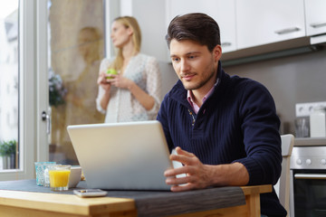 Wall Mural - mann sitzt in der küche und schaut konzentriert auf seinen laptop