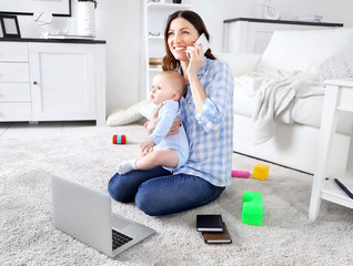 Wall Mural - Beautiful woman with baby boy working from home using laptop