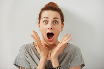 Surprise astonished woman. Closeup portrait woman looking surprised in full disbelief  wide open mouth isolated grey wall background. Positive human emotion facial expression body language. Funny girl